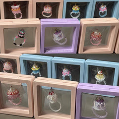 Collection of jewelry boxes with cake rings displayed inside on a gray surface.