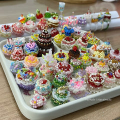 Tray of colorful beaded miniature cakes on a wooden surface